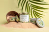 Coco de mer and cashmere candle in a gold tin surrounded by tropical props