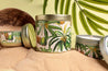 Coco de mer and cashmere candle in a gold tin surrounded by tropical props